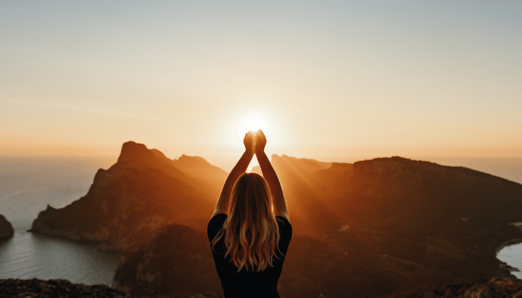 personne qui tient le soleil entre ses mains dans un beau paysage
